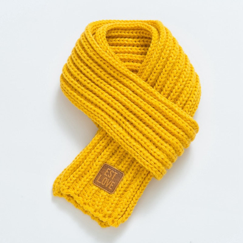 Gelber Strickschal aus Wolle mit "EST LOVE"-Label, modisches Accessoire für kalte Tage.