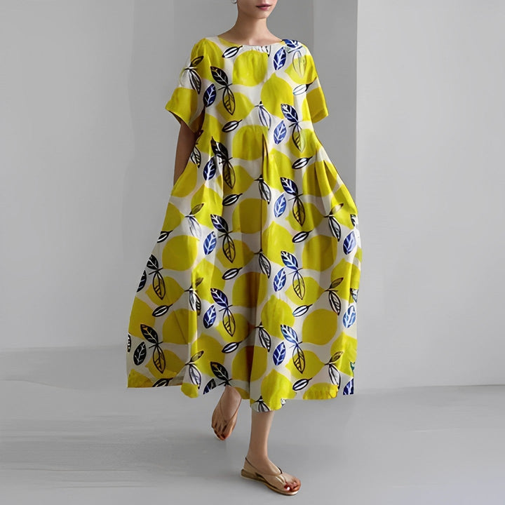 Frau in gelbem Maxikleid mit blauem Blattmuster, Sommermode, lässig, bequem, elegant.
