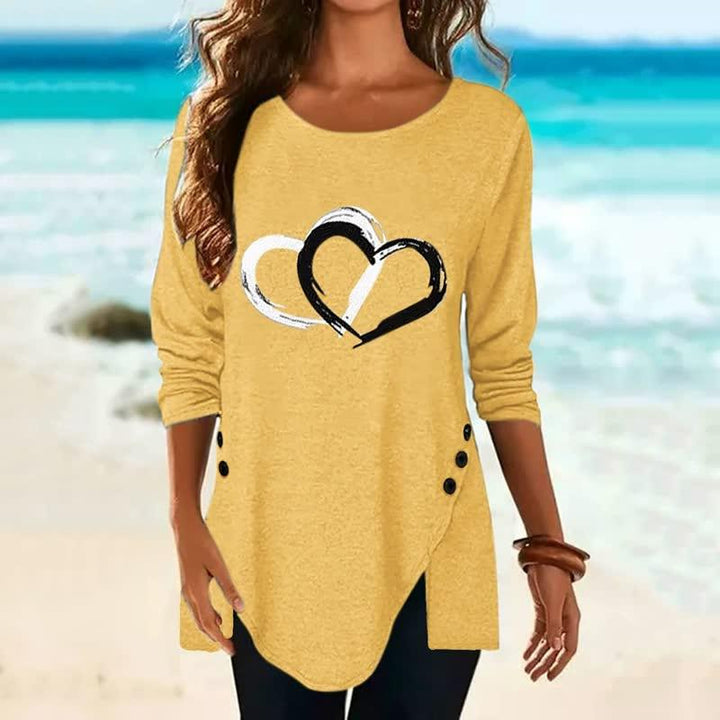 Gelbes Damen-Langarmshirt mit Herzmotiv, Knopfleiste, lässig, Strandhintergrund.