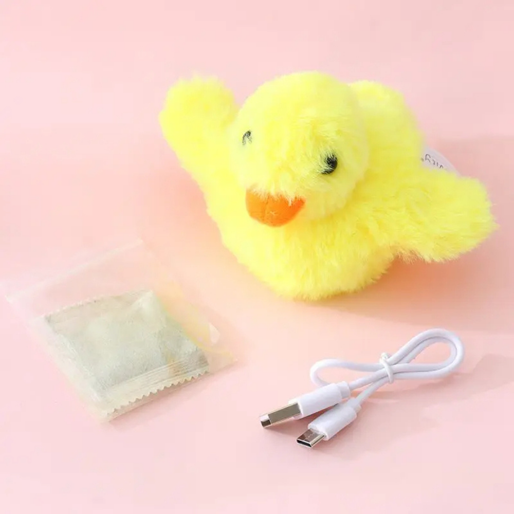 Gelbes Plüschküken mit USB-Kabel und Teebeutel auf rosa Hintergrund.