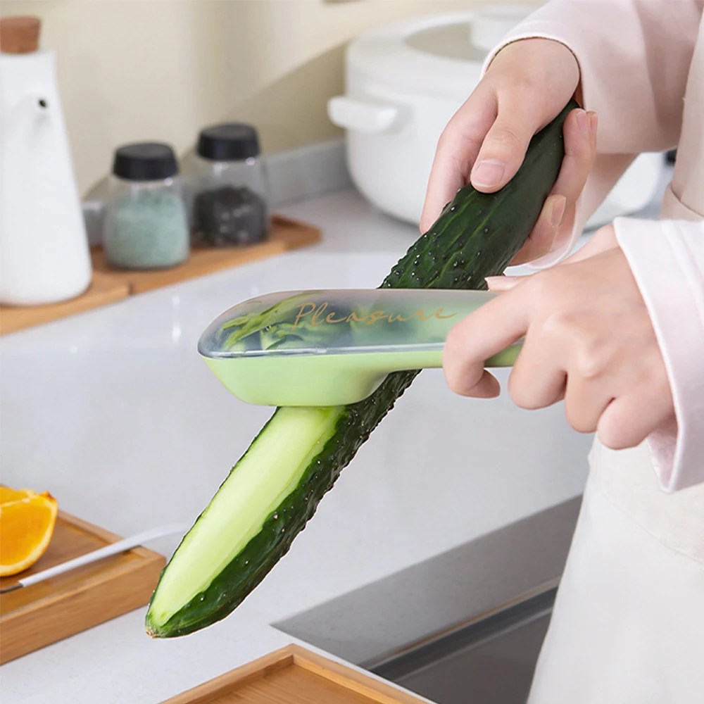 Person schält Gurke mit grünem Edelstahl-Gemüseschäler in moderner Küche.