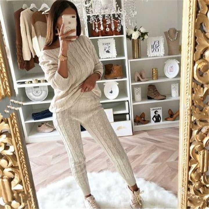 Frau in beigem Strickpullover und Hose, Selfie im Spiegel, modisches Outfit, gemütliches Wohnzimmer.