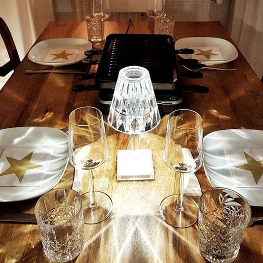 Eleganter Esstisch mit Raclette-Grill, Kristallgläsern und Tellern mit goldenen Sternen.