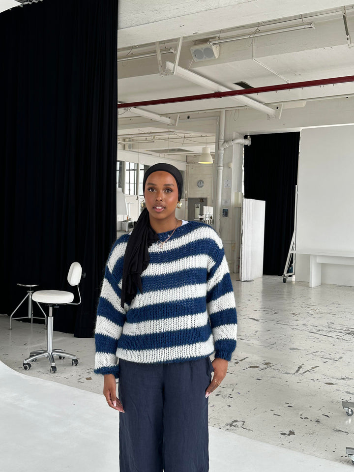Frau in gestreiftem Pullover, Fotostudio, schwarz-weiß, modisch, lässig, modern, urban.