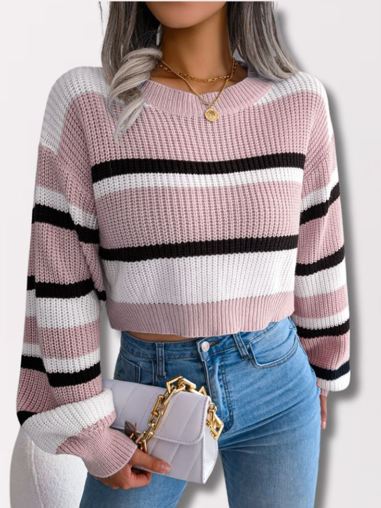 Frau in gestreiftem Strickpullover, rosa, schwarz, weiß, mit Jeans und weißer Handtasche.