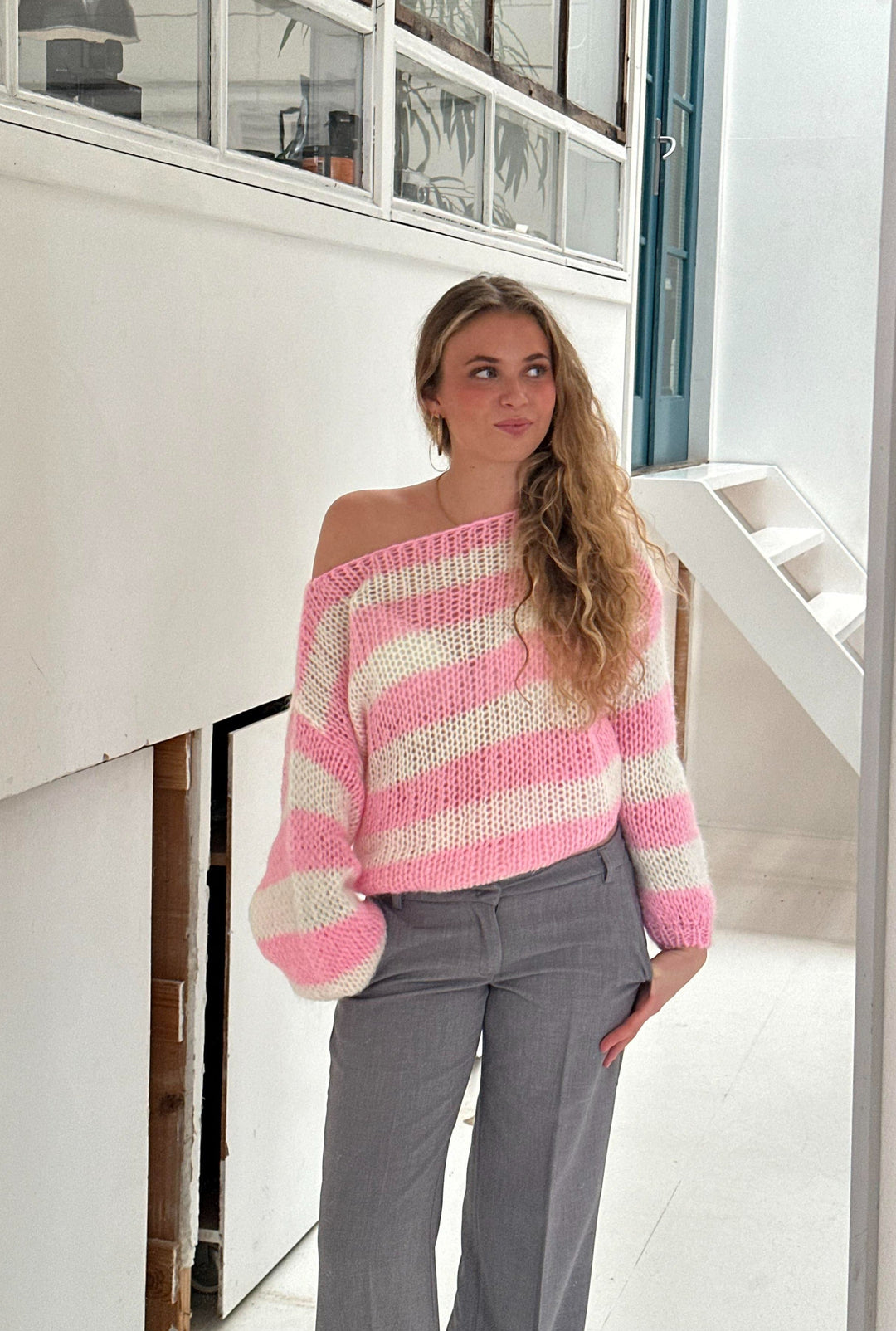 Frau in rosa-weiß gestreiftem Pullover, graue Hose, lässiger Look, modische Kleidung.