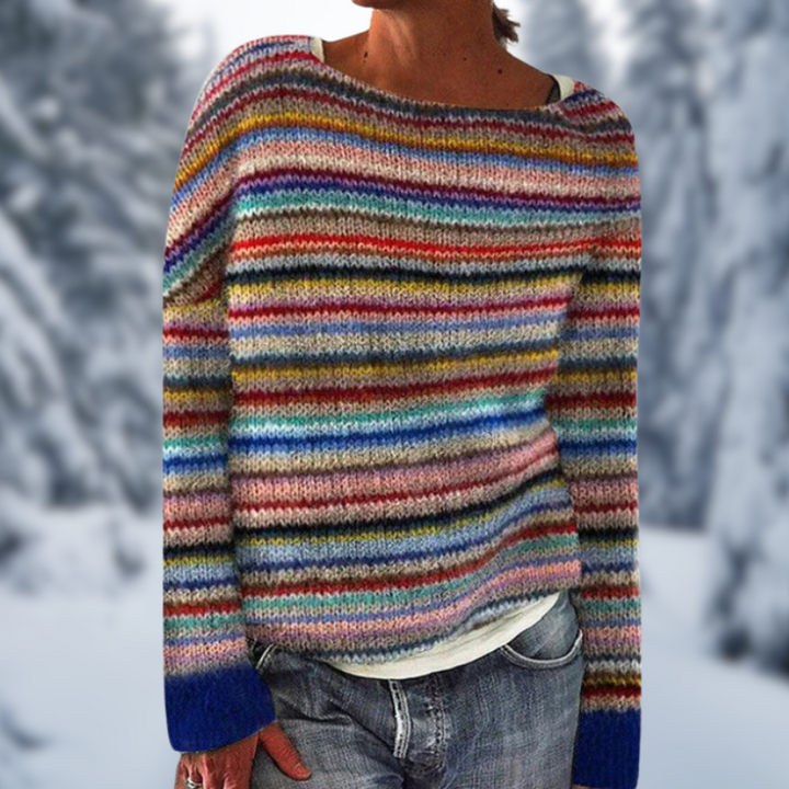 Frau in buntem gestreiftem Pullover vor verschneitem Waldhintergrund.