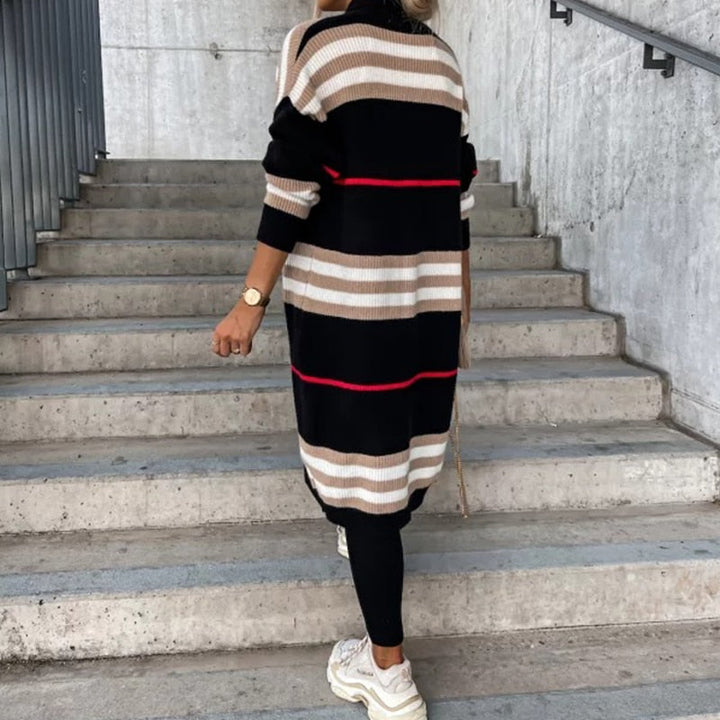 Frau in gestreiftem Strickkleid, schwarz-beige, auf Treppe, modisch, urbaner Stil.