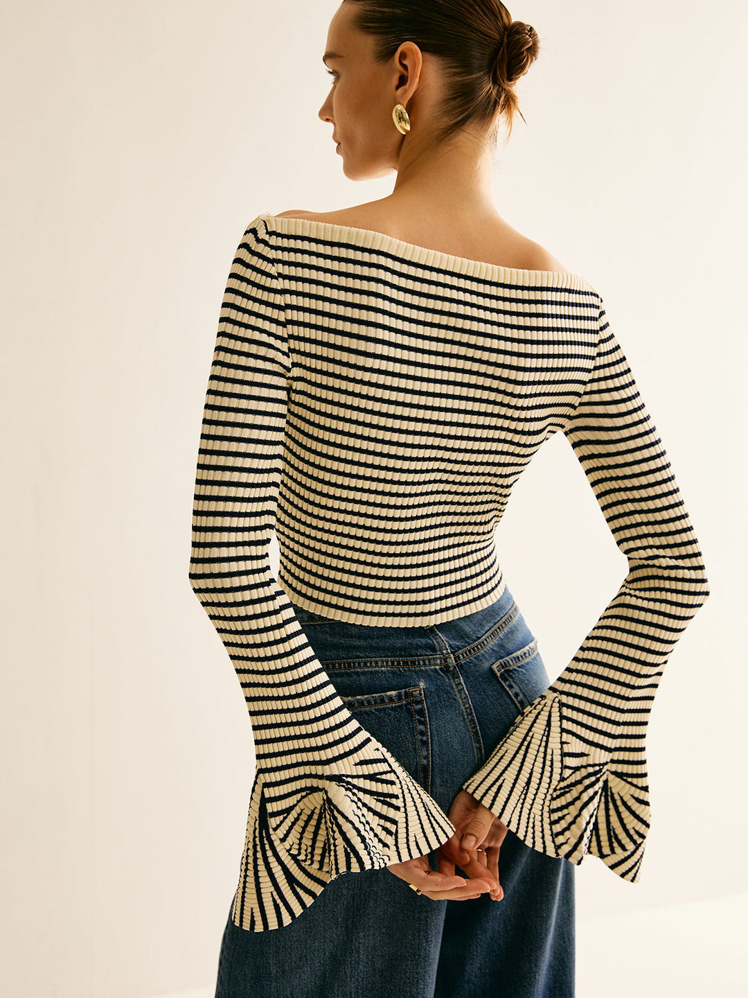 Frau in gestreiftem Pullover mit Trompetenärmeln, blau-weiß, modisch, elegant, Rückansicht.