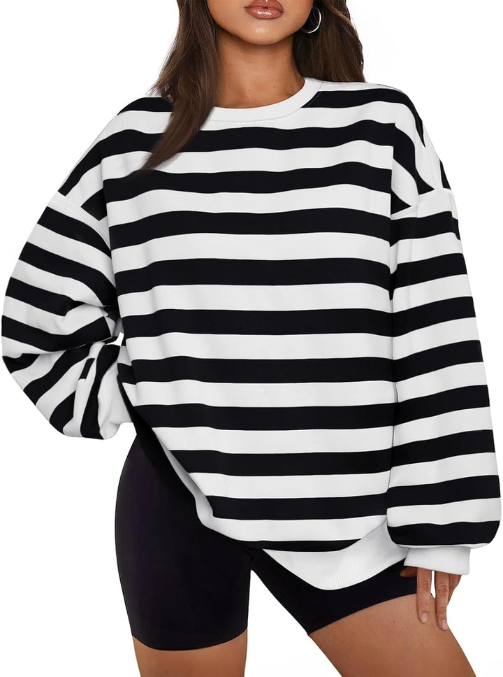 Frau in schwarz-weiß gestreiftem Oversize-Pullover, modisch, lässig, Herbstmode.