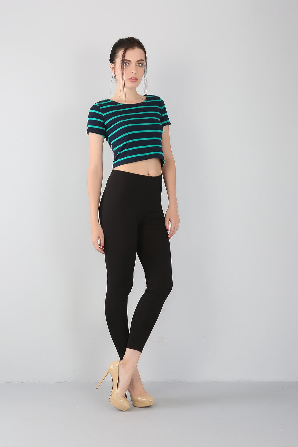 Frau in gestreiftem T-Shirt und schwarzer Leggings, beige High Heels, modisch, lässig.