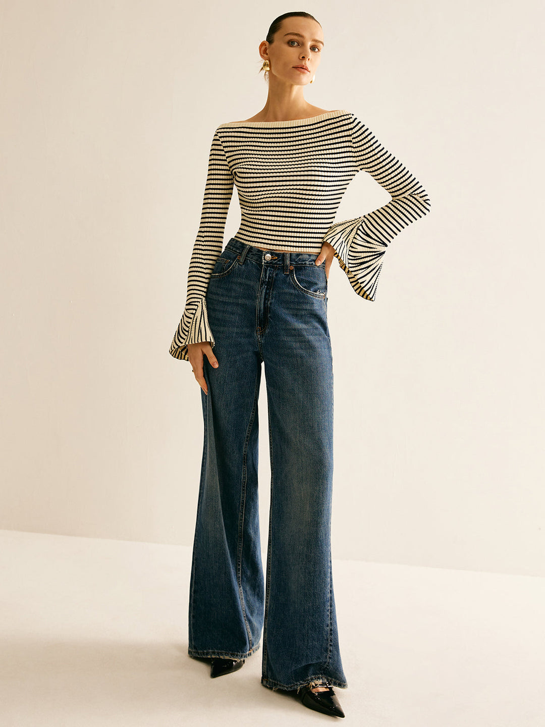 Frau in gestreiftem Pullover und blauer Schlaghose, modisch, elegant, zeitloses Outfit.