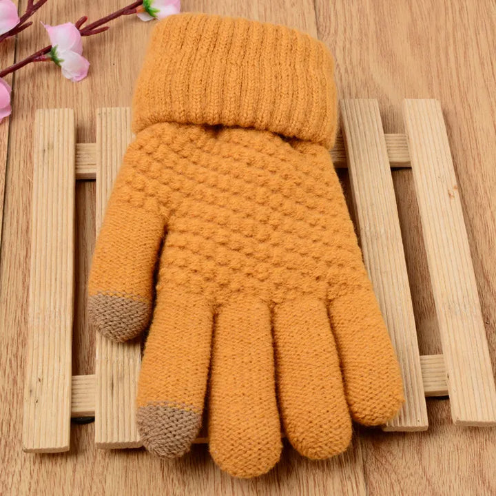 Gelbe gestrickte Handschuhe aus Wolle mit Touchscreen-Funktion auf Holzuntergrund.