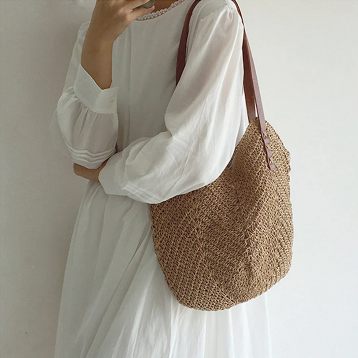 Frau in weißem Kleid mit brauner Strohtasche, modisch, Sommeraccessoire, lässiger Stil.