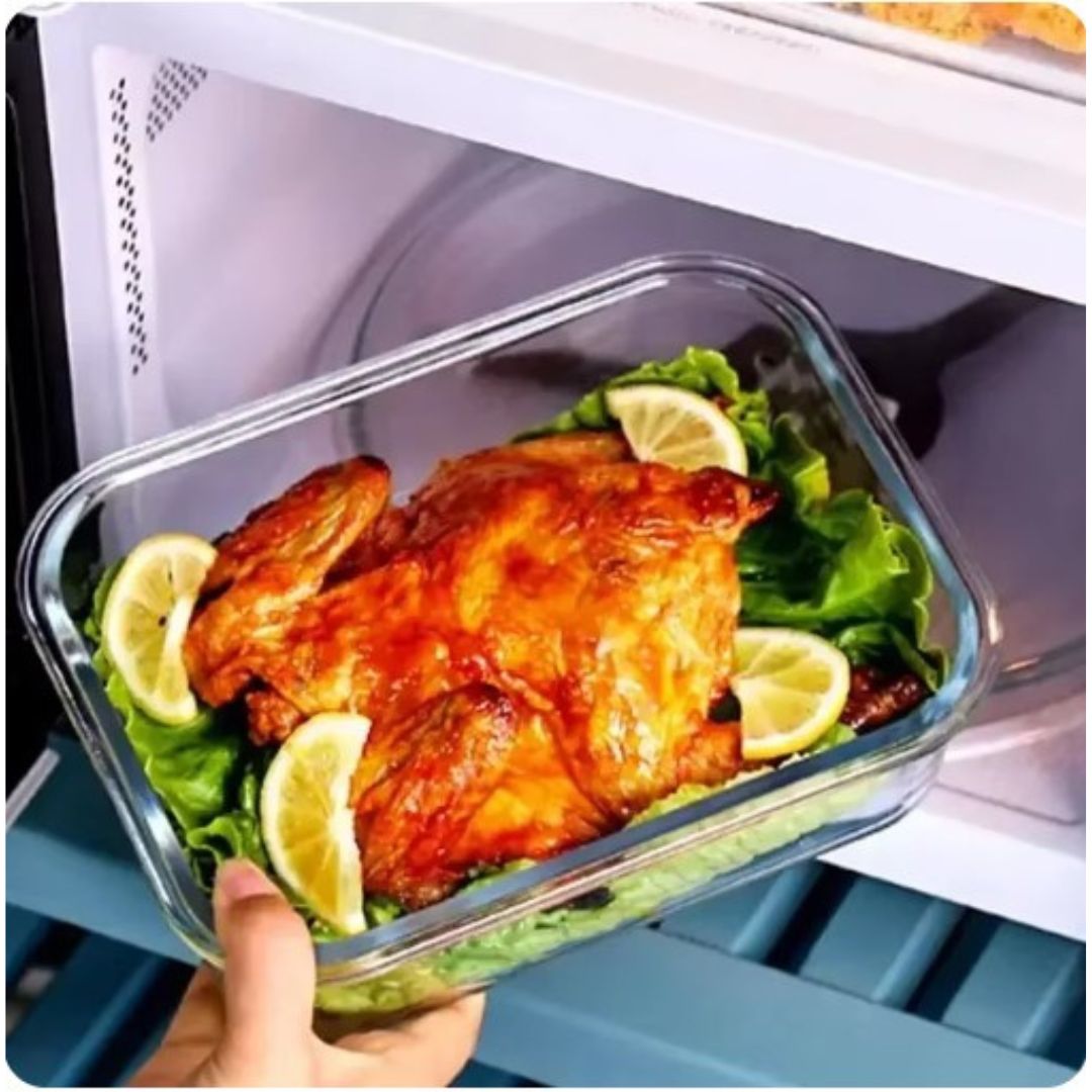 Glasbehälter mit gebratenem Hähnchen, Zitronenscheiben und Salat in der Mikrowelle.
