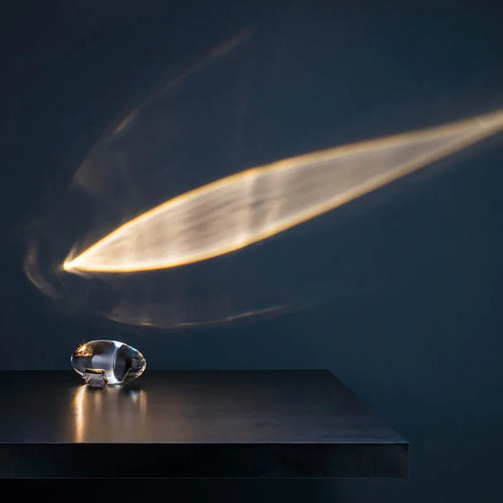 Kristallglas-Skulptur auf Tisch, reflektiert Lichtstrahl, modernes Design, dunkler Hintergrund.