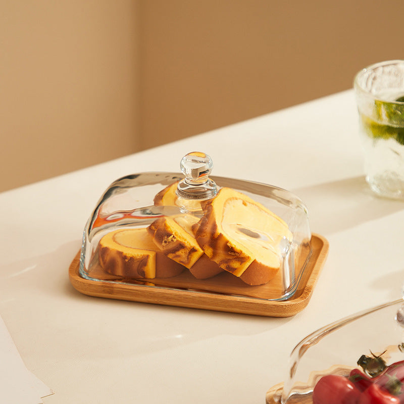 Glas-Käseglocke mit Holzplatte, enthält geschnittenen Kuchen, ideal für Küche und Tischdekoration.