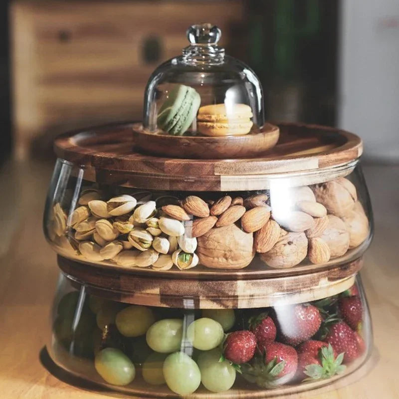 Glas-Etagere mit Holzdeckeln, gefüllt mit Nüssen, Macarons, Trauben und Erdbeeren.
