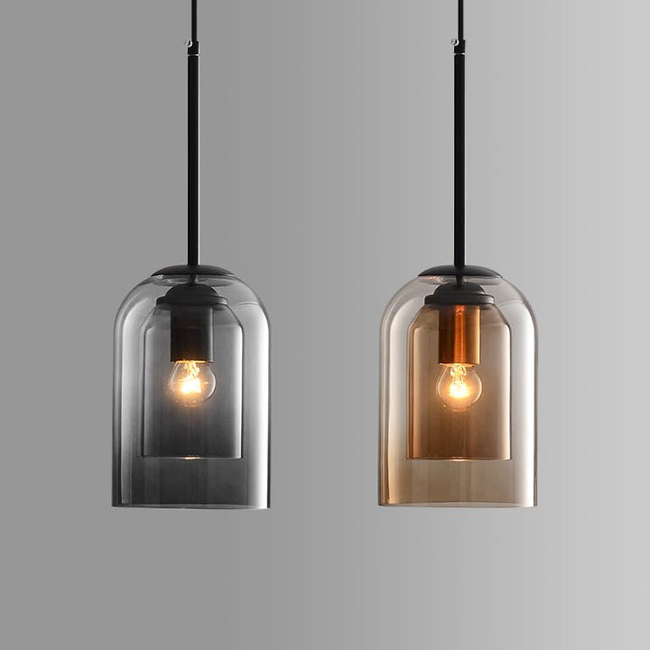 Zwei moderne Hängelampen aus Glas, schwarz und gold, mit sichtbaren Glühbirnen, minimalistisch.