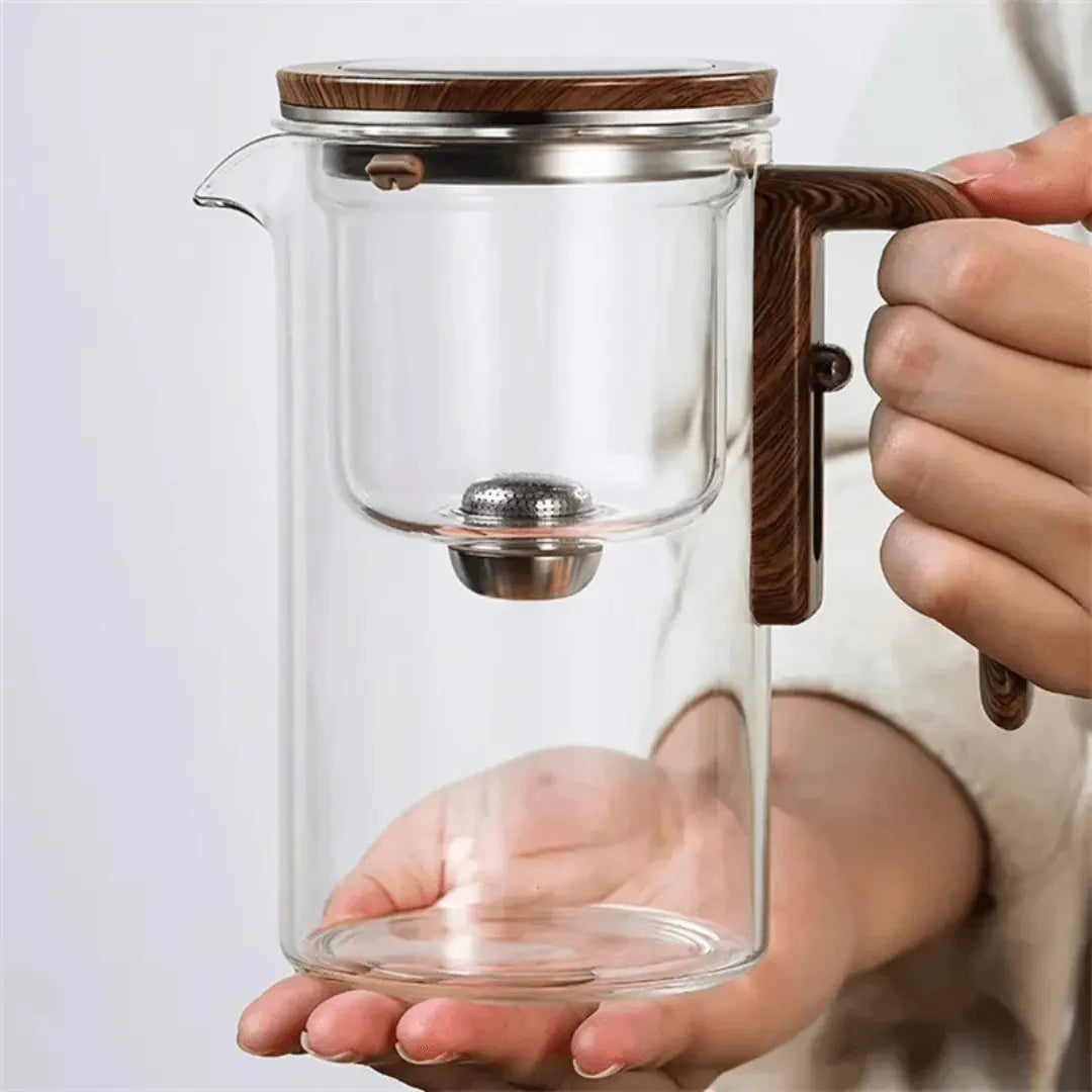 Glas-Teekanne mit Holzgriff, Edelstahlfilter, modernes Design, transparent, handgehalten.