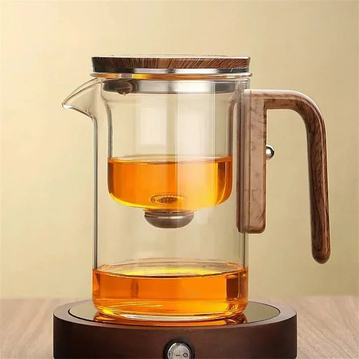 Glas-Teekanne mit Holzgriff, doppelwandig, modern, transparent, auf Holzuntersetzer.