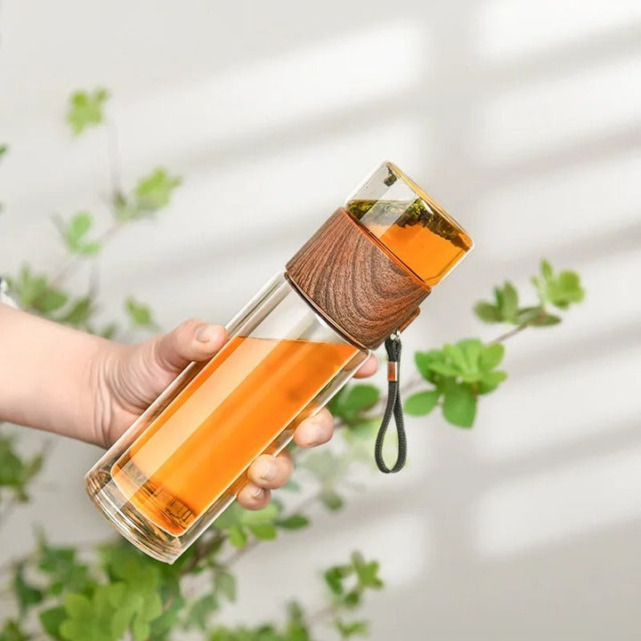 Hand hält Glaswasserflasche mit Holzdeckel, Tee, umweltfreundlich, wiederverwendbar.