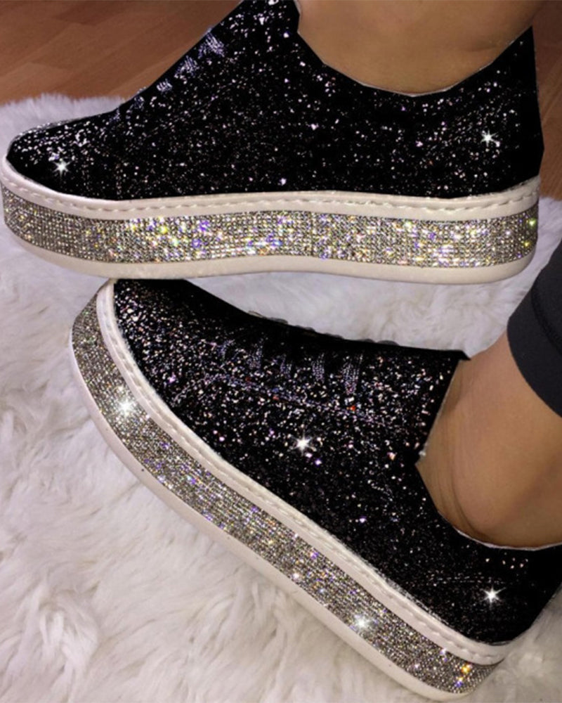 Schwarze Glitzer-Sneaker mit Strasssohle auf weißem Teppich, modische Damenschuhe.