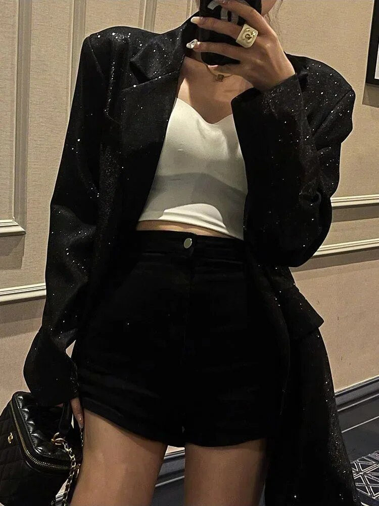 Frau in schwarzem Pailletten-Blazer, weißem Top und schwarzem Rock, eleganter Abendlook.