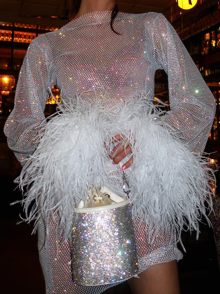 Funkelndes silbernes Paillettenkleid mit weißen Federn und glitzernder Handtasche in Barumgebung.