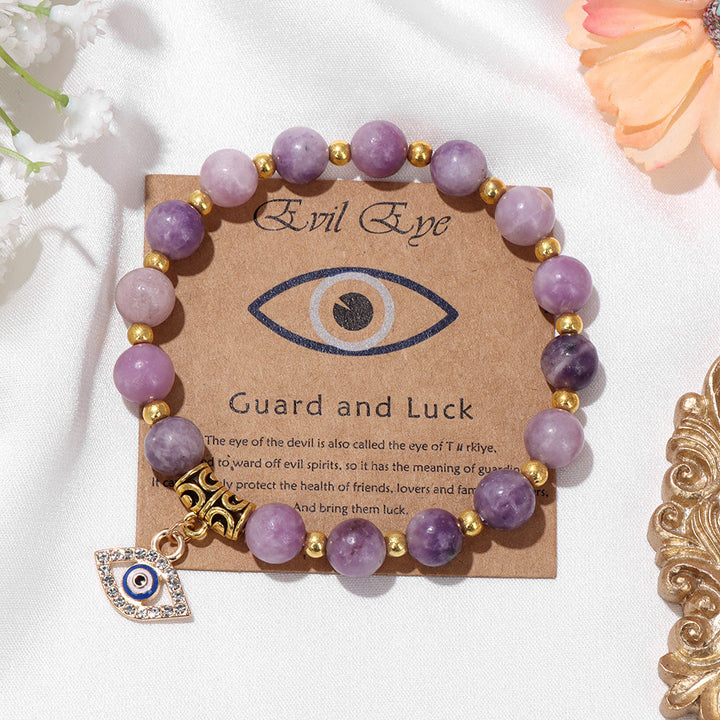 Lila Naturstein-Armband mit türkischem Auge, goldenen Perlen und Glücksbringer auf Karte.