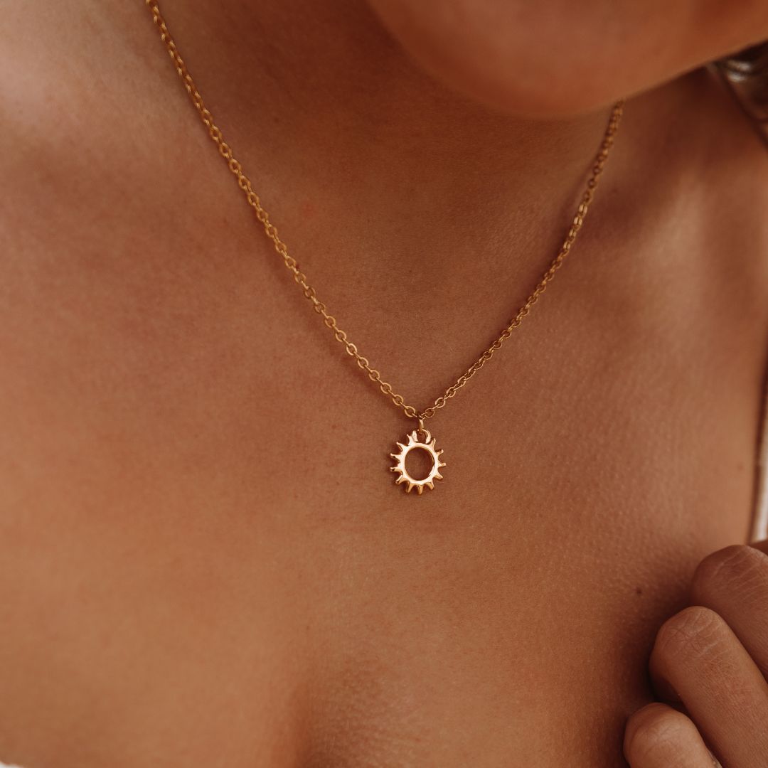Goldene Sonnenanhänger-Halskette auf Haut, Schmuck, Damenmode, Accessoire, Geschenkidee.