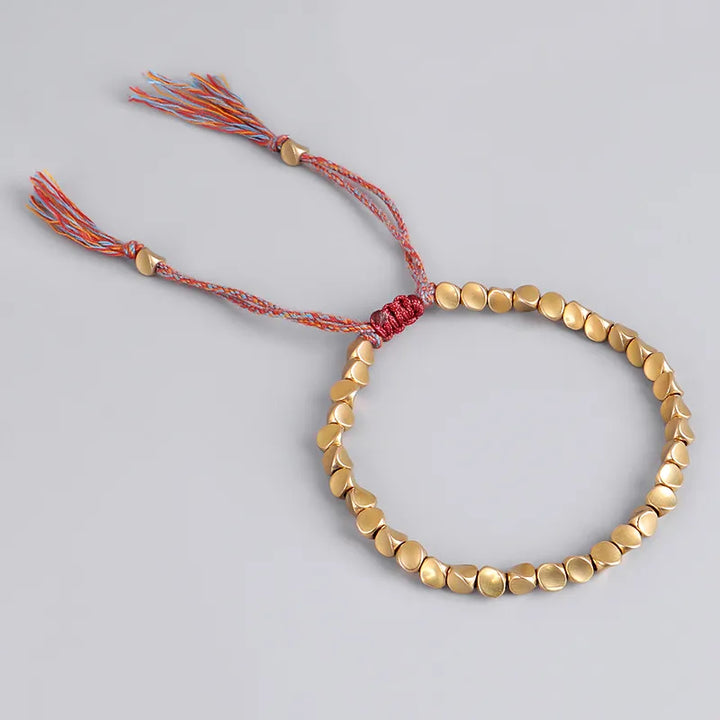 Goldfarbenes Armband mit runden Perlen und buntem Kordelverschluss, handgefertigter Schmuck.