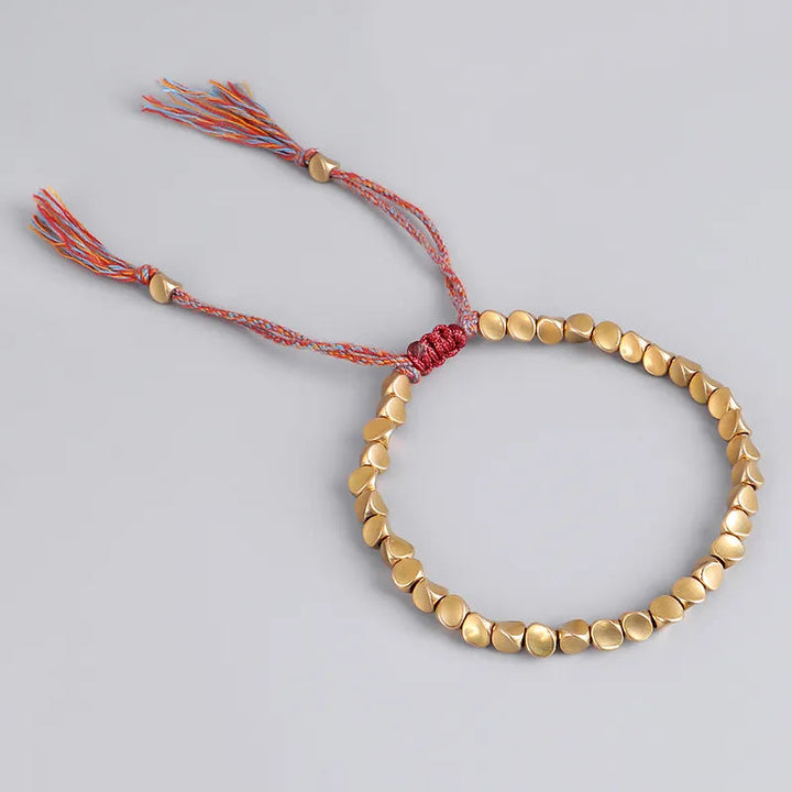 Goldenes Perlenarmband mit verstellbarem, buntem Kordelverschluss, handgefertigt.