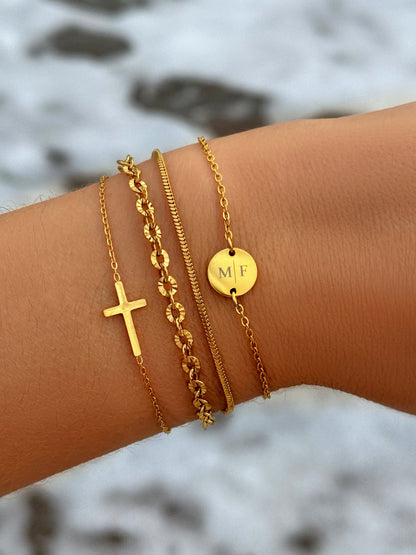 Goldene Armbänder-Set mit Kreuz und Initialen-Anhänger auf Handgelenk, modischer Schmuck.