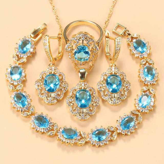 Goldene Schmuckset mit blauen Zirkonia, bestehend aus Armband, Ring und Ohrringen.