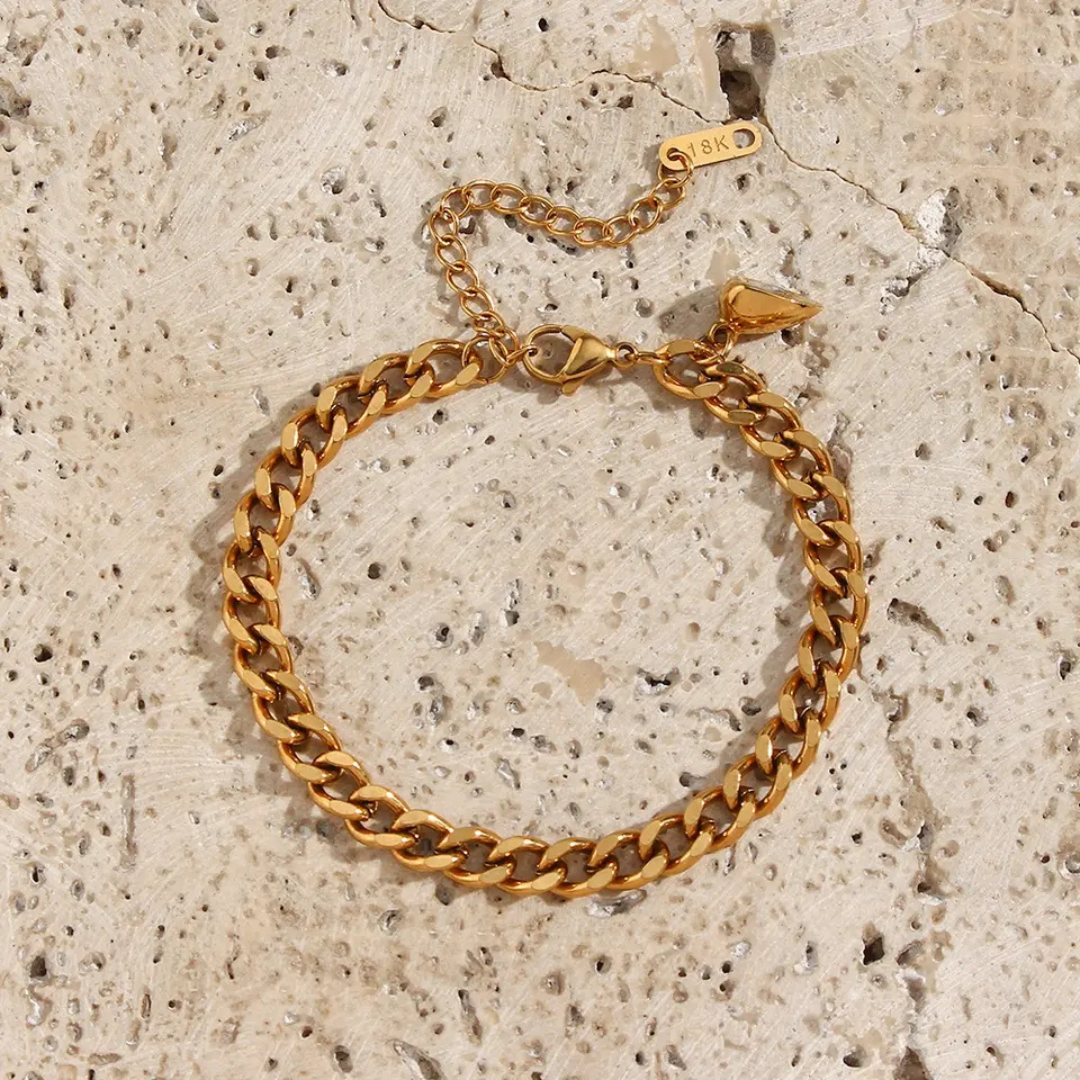 Goldenes Armband aus Edelstahl, Kettenglied-Design, verstellbar, auf hellem Steinuntergrund.