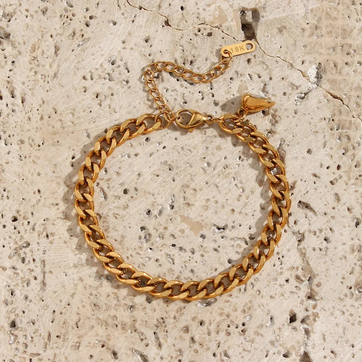 Goldenes Armband aus Edelstahl, Kettenglied-Design, verstellbar, auf hellem Steinuntergrund.