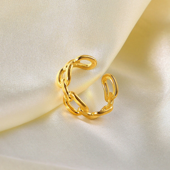 Goldener Kettenring auf cremefarbenem Satin, eleganter Schmuck, modisches Accessoire.