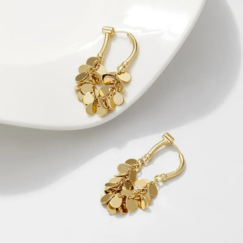 Goldene Ohrringe mit Blattdesign auf weißem Teller, modischer Schmuck, elegantes Accessoire.