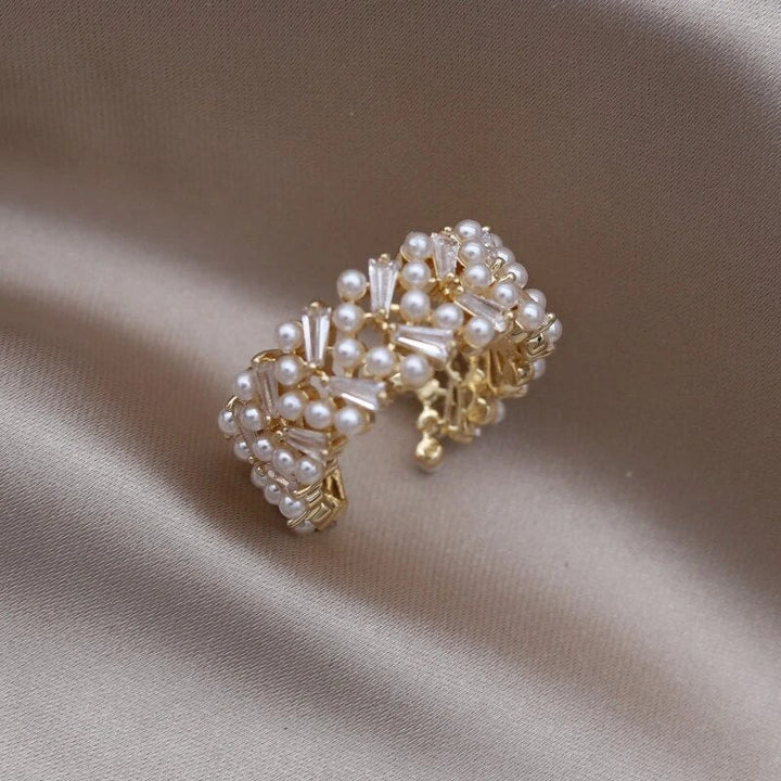Goldener Perlenring auf Seidenstoff, eleganter Schmuck, luxuriöses Design, Damenaccessoire.