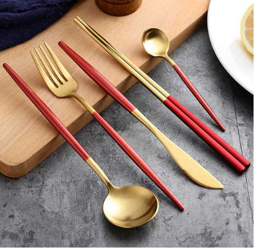 Rotes und goldenes Besteckset aus Edelstahl, bestehend aus Gabel, Messer, Löffel und Essstäbchen.