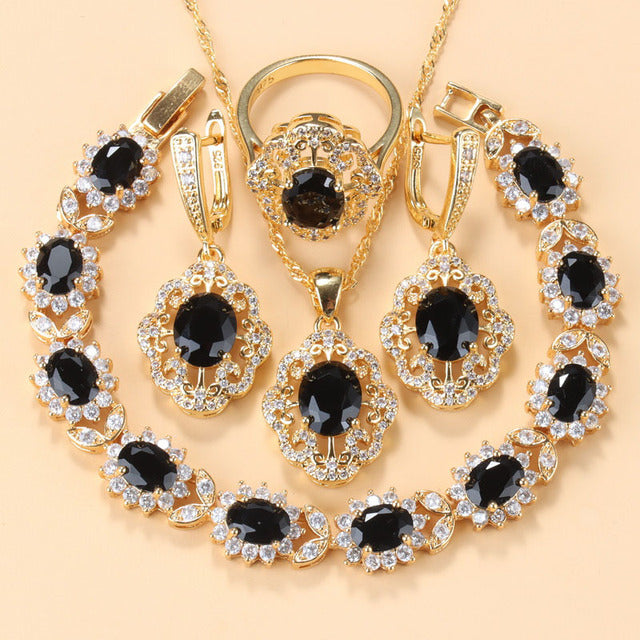 Goldene Schmuckset mit schwarzen Zirkonia, bestehend aus Armband, Ring, Ohrringen und Anhänger.