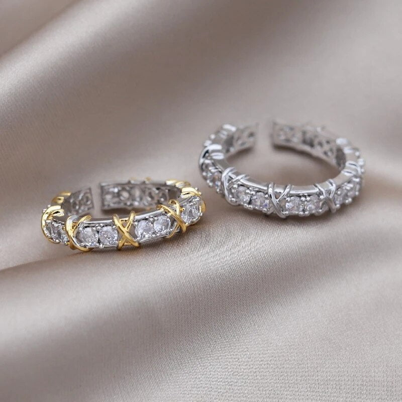 Zwei elegante Ringe mit Diamanten, einer in Gold, der andere in Silber, auf Seidenstoff.