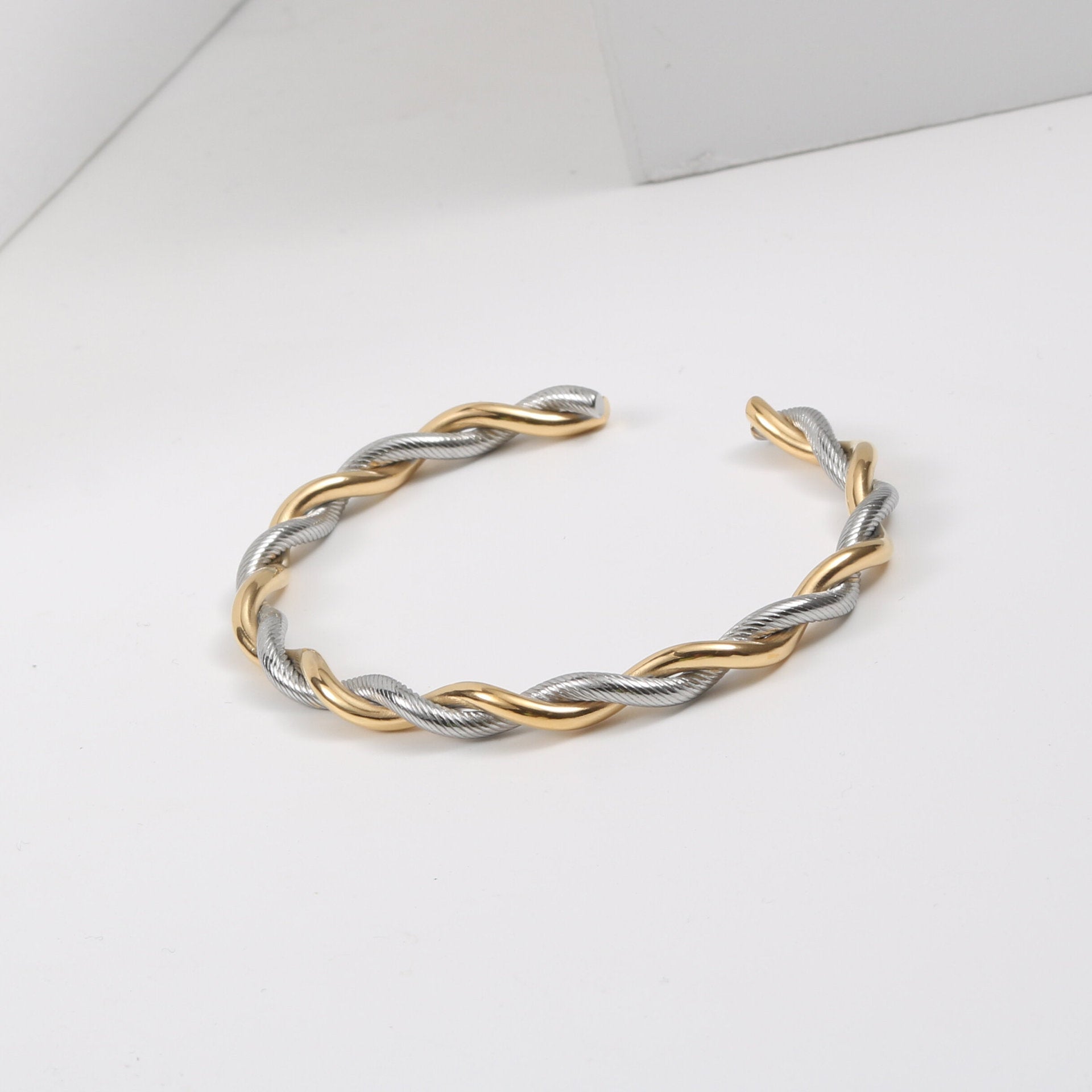Goldene und silberne Twist-Armreif aus Edelstahl für Damen, modisches Design.