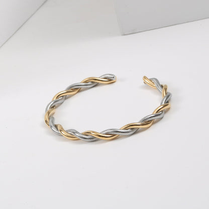 Goldene und silberne Twist-Armreif aus Edelstahl für Damen, modisches Design.