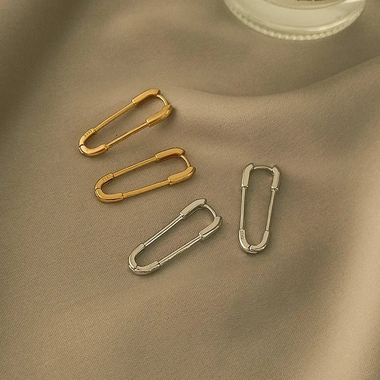 Goldene und silberne Karabinerhaken auf beigem Stoff, Schmuckzubehör, elegant und modern.