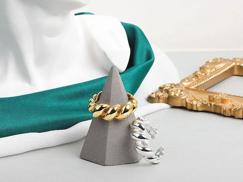 Goldener und silberner Ring auf grauem Kegel, Schmuck, Modeaccessoire, elegantes Design.