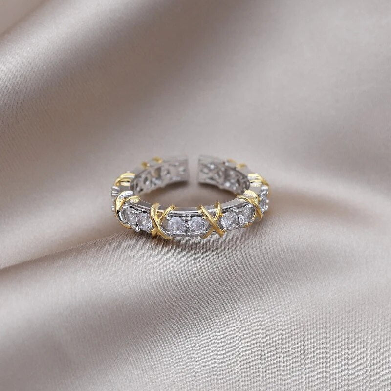 Goldener und silberner Ring mit Zirkonia-Steinen auf beigem Stoffhintergrund.