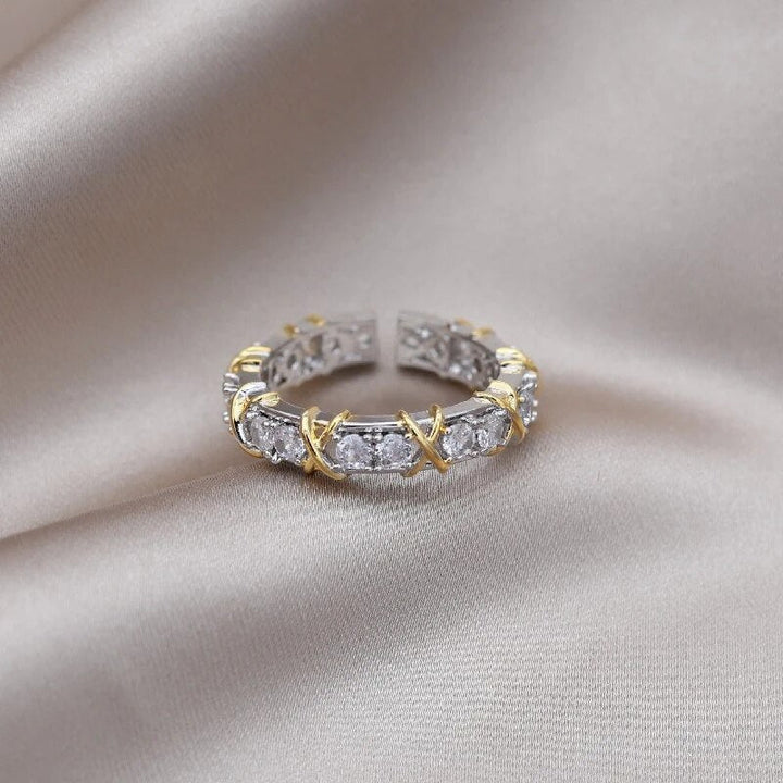 Goldener und silberner Ring mit Zirkonia-Steinen auf beigem Stoffhintergrund.