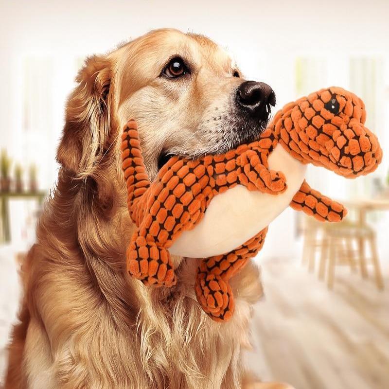 Golden Retriever mit orangefarbenem Dinosaurier-Plüschtier im Maul, Hundespielzeug, Wohnzimmer.